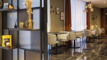 Un vestíbulo de hotel con mostrador de recepción, zona de estar y una pared decorativa con un libro y un jarrón.