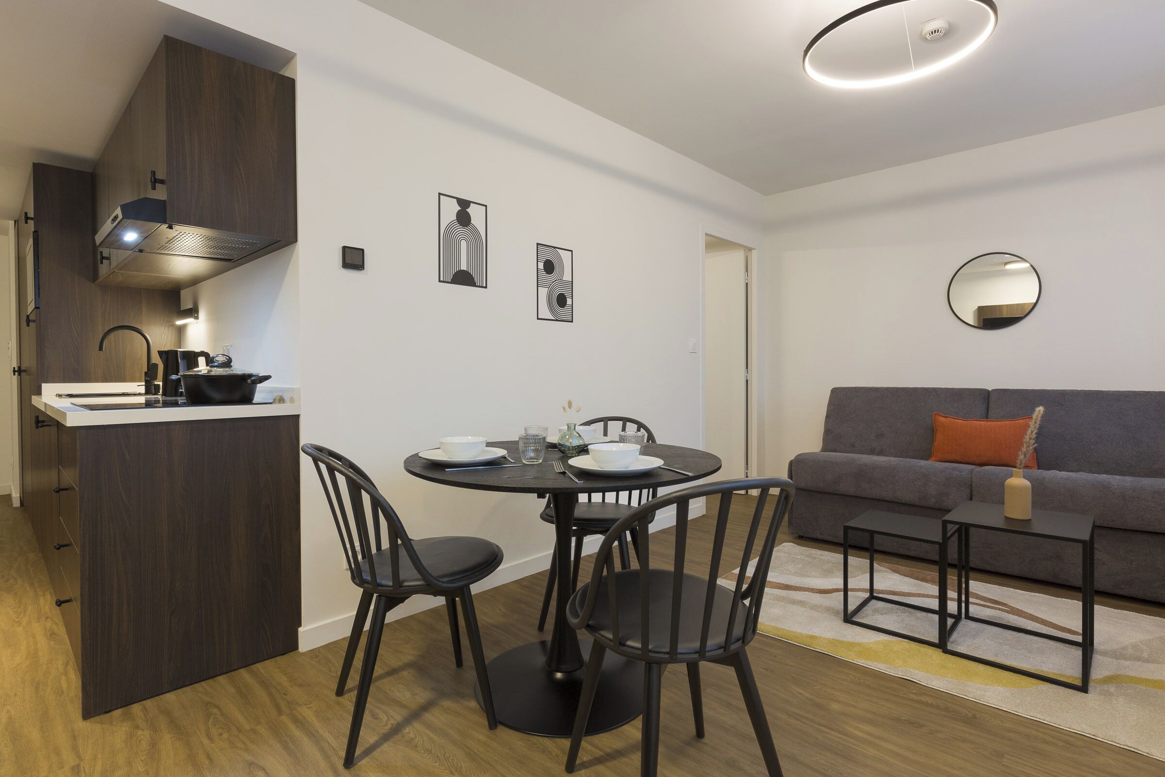 Un espace de vie compact comprenant un coin cuisine, un coin repas et un coin salon.