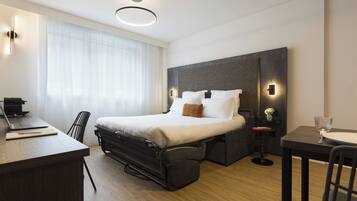 Quarto de hotel moderno com cama, escrivaninha e área de estar.