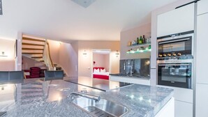 Eine moderne Küche mit Granitabdeckung, Edelstahlspüle und eingebautem Backofen.