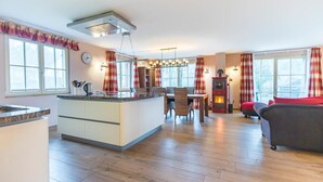 Eine moderne Küche mit einer zentralen Kochinsel, einem Essbereich mit Stühlen, einem Sofa und einem Kamin.