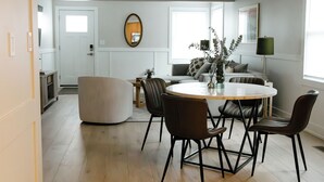 Een moderne keuken met een eethoek, met een ronde tafel met stoelen, een bank en een grote spiegel aan de muur.
