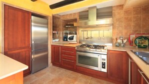 Une cuisine dotée de meubles en bois, d’appareils électroménagers en acier inoxydable et d’un dosseret carrelé.