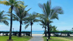 Uma trilha pavimentada bordeada por palmeiras que leva a uma praia.