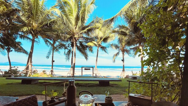 Uma área de refeições à beira-mar com uma mesa posta para dois, com vista para o oceano.