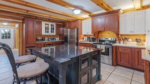 Una cocina con vigas de madera, una isla central, un refrigerador, estufa y armarios.