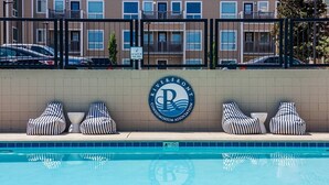 A swimming pool with lounge chairs and a sign indicating no glass in the pool area. - Music City Living - 2BR/2BA Riverfront Paradise with FREE PARKING (Nashville)