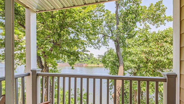 A covered balcony with a view of a river and trees.