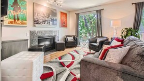 A modern living room with a fireplace, leather sofas, a patterned rug, and artwork on the walls.
