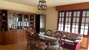 A dining area with a wooden table and chairs, a cabinet with glass doors, and a sofa. - Carpenter's house (Crecente)