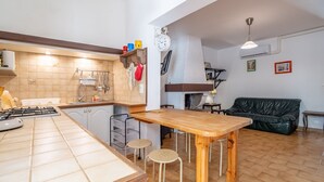 Une cuisine avec une table et des tabourets en bois, un poêle et un évier.