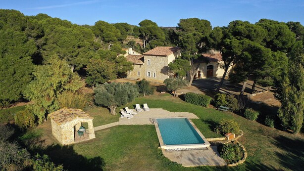 Una villa con piscina, arquitectura de piedra y un jardín exuberante.