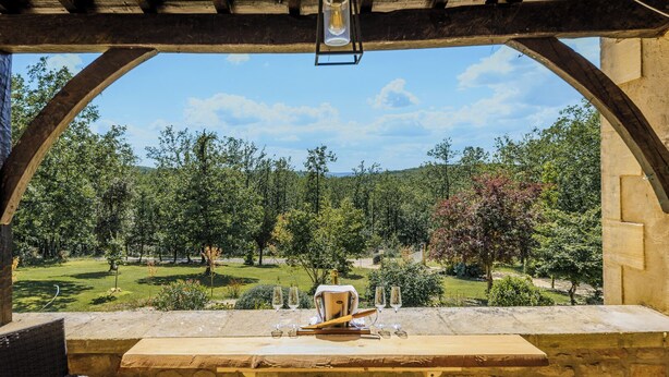 An outdoor dining area with a stone table, two chairs, and a view of a lush garden. - Rosepeche, a beautiful villa with a castle feel (Les Eyzies)