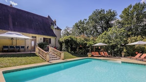 A swimming pool with lounge chairs and a covered patio area. - Rosepeche, a beautiful villa with a castle feel (Les Eyzies)