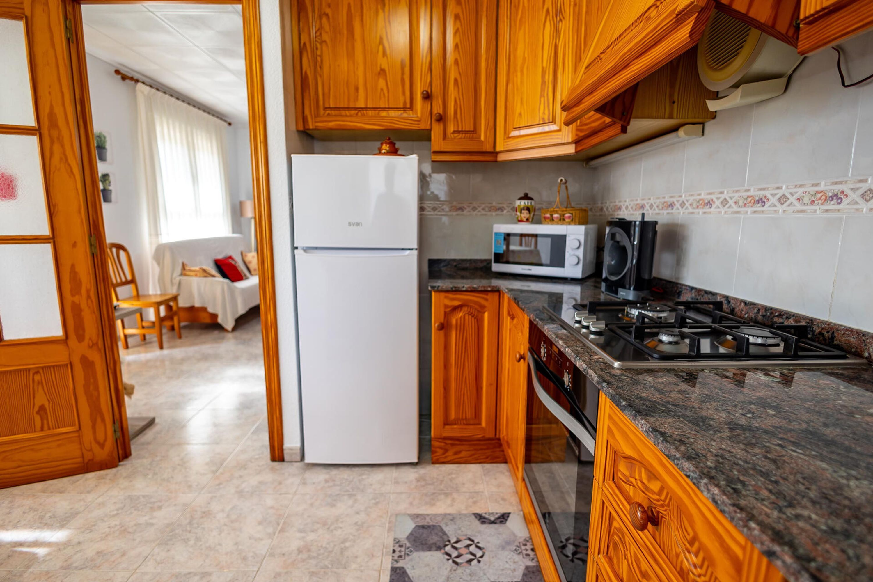A kitchen with wooden cabinets, a white refrigerator, a microwave, and a gas stove.