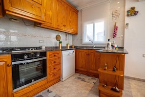 A kitchen with wooden cabinets, a dishwasher, and a stove.