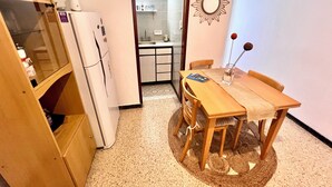 A compact kitchen with a refrigerator, a dining table with chairs, and a small island with a sink.