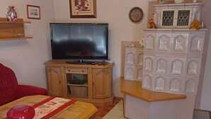 A living room with a television, a red sofa, a white sofa, a wooden cabinet, and a decorative shelf. - Cozy and large vacation apartment on the Nömerberg (Windorf)