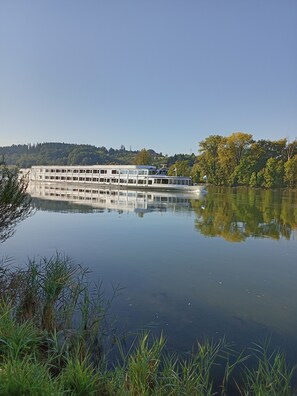 A riverboat docked at a calm river with a forested hillside in the background. - Cozy and large vacation apartment on the Nömerberg (Windorf)