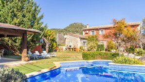 A swimming pool with a stone house in the background. - Port Andratx Family Holiday House With Pool (Andraitx)