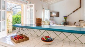 A kitchen with a blue countertop, a television mounted on the wall, and a window with curtains. - Port Andratx Family Holiday House With Pool (Andraitx)