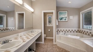 A bathroom with two sinks, a bathtub, and a large mirror.