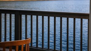 A view from a balcony overlooking a lake with forested hills in the background.