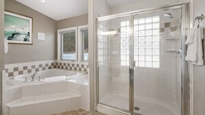 A modern bathroom with a large bathtub, a walk-in shower, and a window providing natural light.