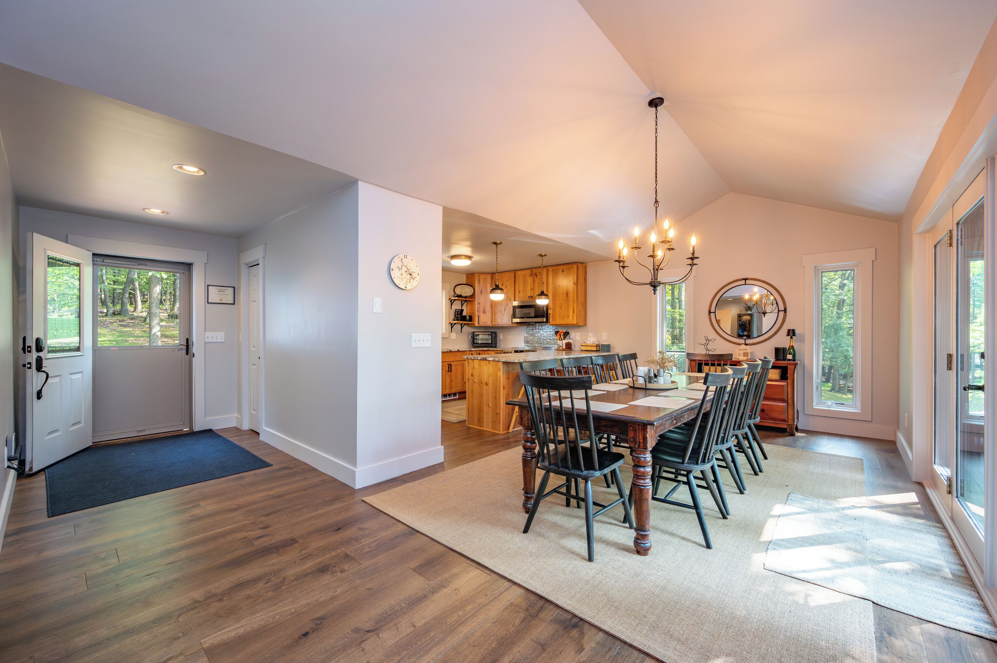 A spacious kitchen with wooden cabinets, a dining area with a large table and chairs, and a chandelier.