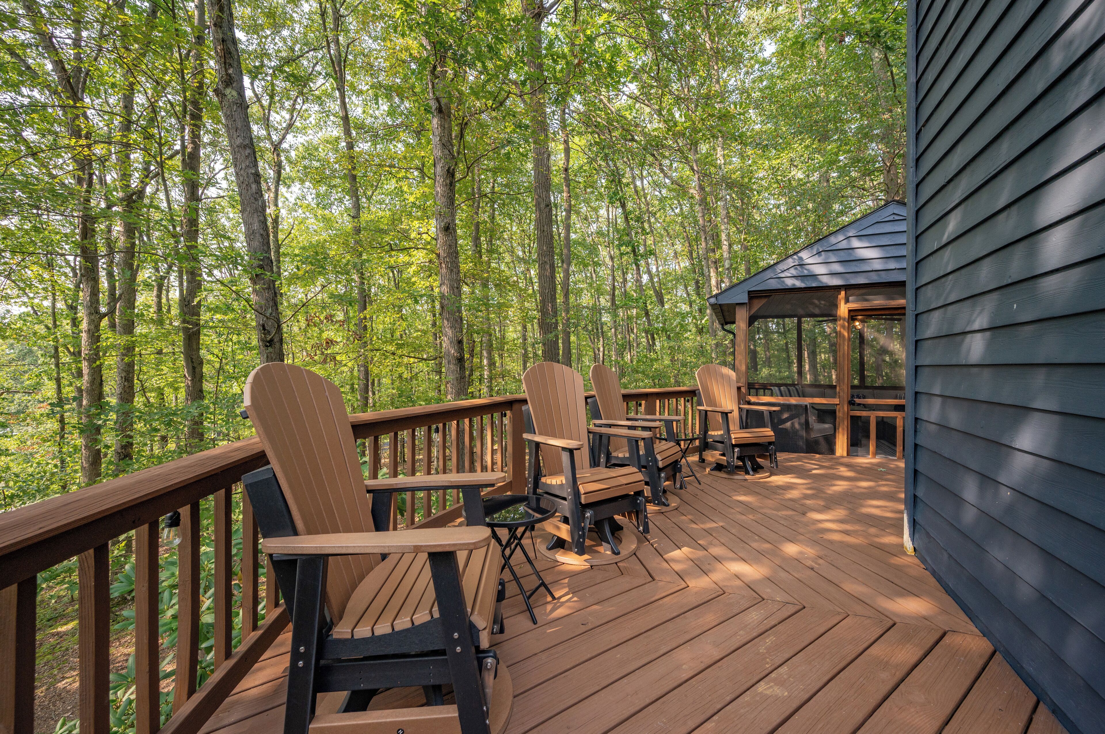 A wooden deck with Adirondack chairs and a gazebo, surrounded by a forest.
