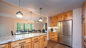 A spacious kitchen with wooden cabinets, a large island, stainless steel appliances, and pendant lighting.
