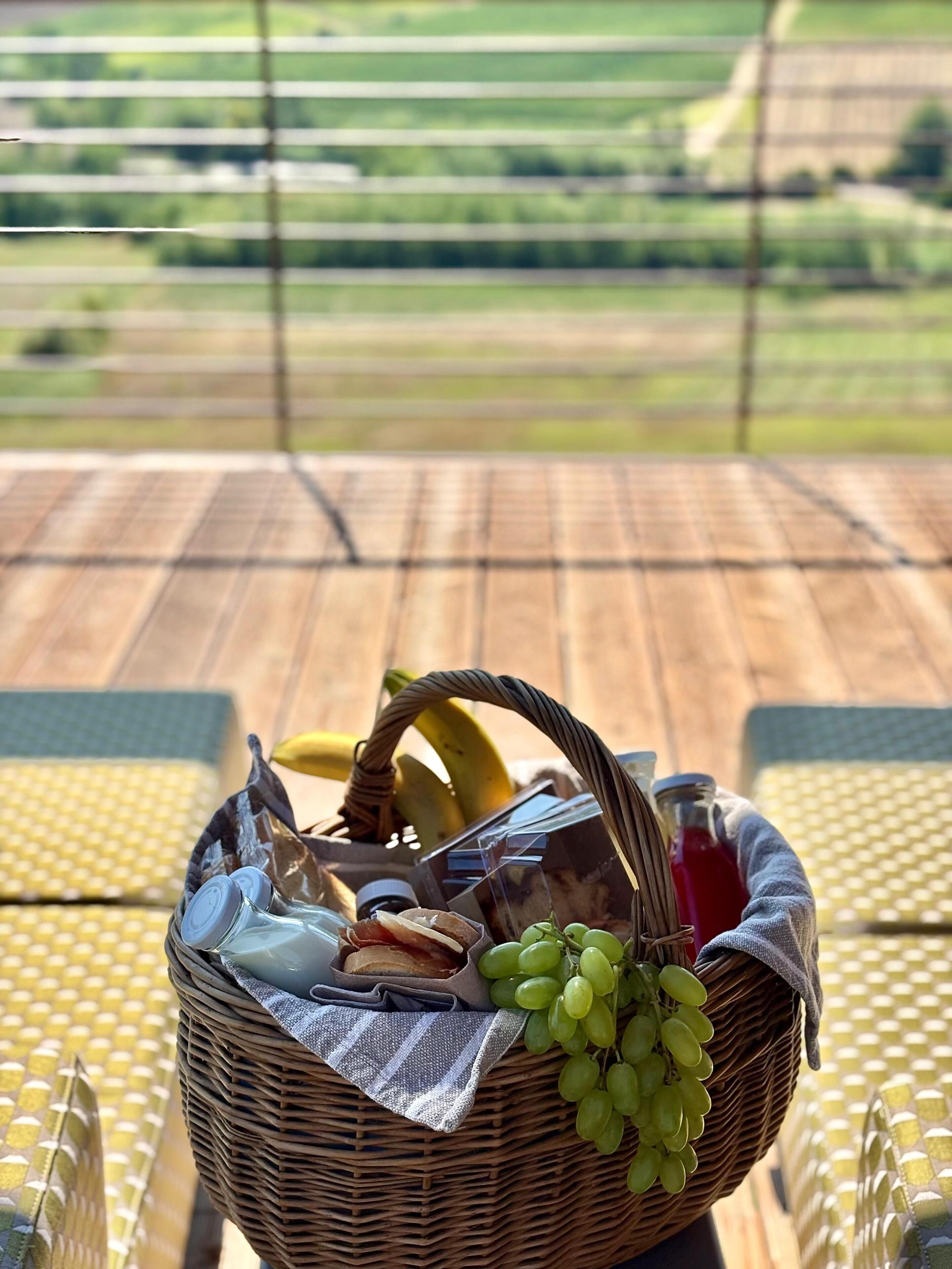 A wicker basket filled with food items on a table with a checkered tablecloth.