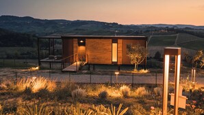 Una casa moderna con fachada de madera, una escalera y vistas del campo circundante.