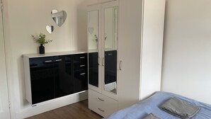 Een slaapkamer met een kledingkast, een bed en een spiegel met hartvormige uitsparingen.