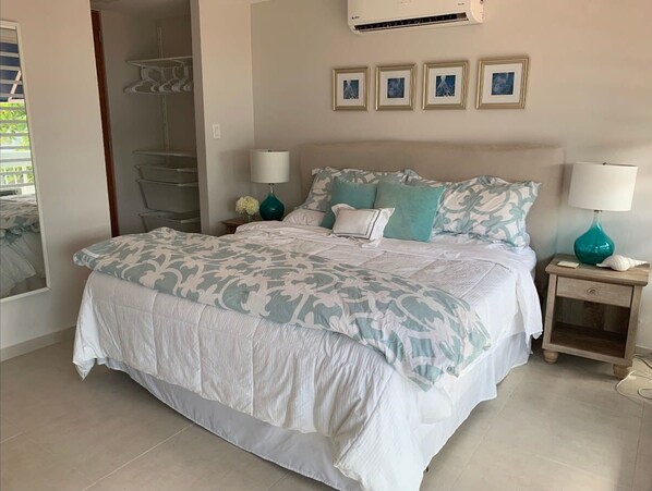 Un dormitorio con una cama grande, dos mesitas de noche, un armario y un ventilador de techo.