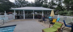 A covered outdoor area with a pool, lounge chairs, and a gazebo. - 2-BR Getaway w/ HUGE screened porch, Golf Cart, Pool, & Boat Ramp near Wolf Bay (Elberta)