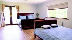 A bedroom with two beds, a window, a radiator, and a door leading outside.
