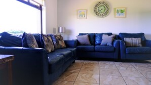 A living room with a sectional sofa, a lamp, and two framed pictures on the wall.