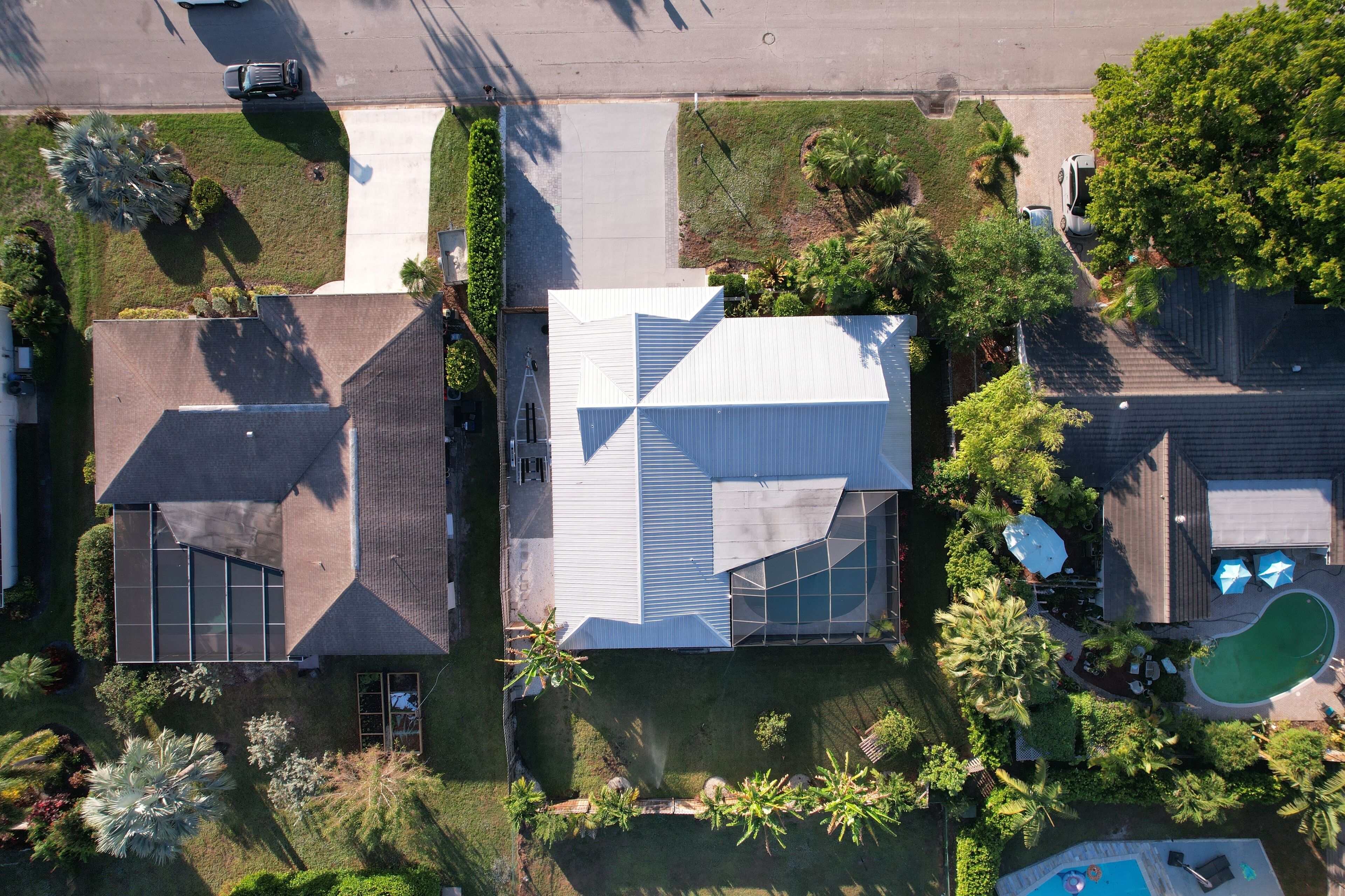An aerial view of a residential area with modern houses, a swimming pool, and well-maintained lawns.