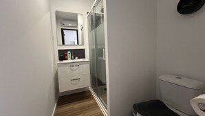 Un bany compacte amb un rentapeus blanc, un mirall a sobre i un vàter.