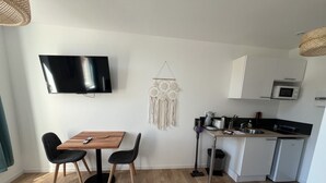 A compact living space with a dining area, kitchenette, and a mounted TV. - Le Boheme, studio 2p (Lens)