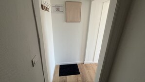 A hallway with a black doormat, a framed artwork on the wall, and a sign with a no-smoking symbol. - Le Boheme, studio 2p (Lens)