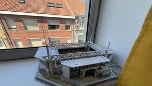 A model of a stadium with a roof and seating areas, placed on a windowsill. - Le studio Sang & Or, 2p (Lens)