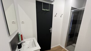 A bathroom with a white sink, a black door, and a glass shower enclosure. - Le studio Sang & Or, 2p (Lens)