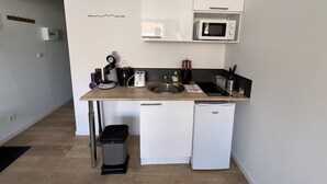 A compact kitchen with a microwave, coffee maker, and a small refrigerator. - Le studio Sang & Or, 2p (Lens)