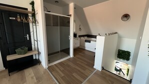 A modern apartment with a sliding glass door leading to a balcony, a kitchenette, and a dining area with a table and chairs. - Le Jardin Botanique : Balnéo 2p (Lens)