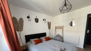 A bedroom with a bed, a bedside table, a hanging light fixture, and wall decorations.