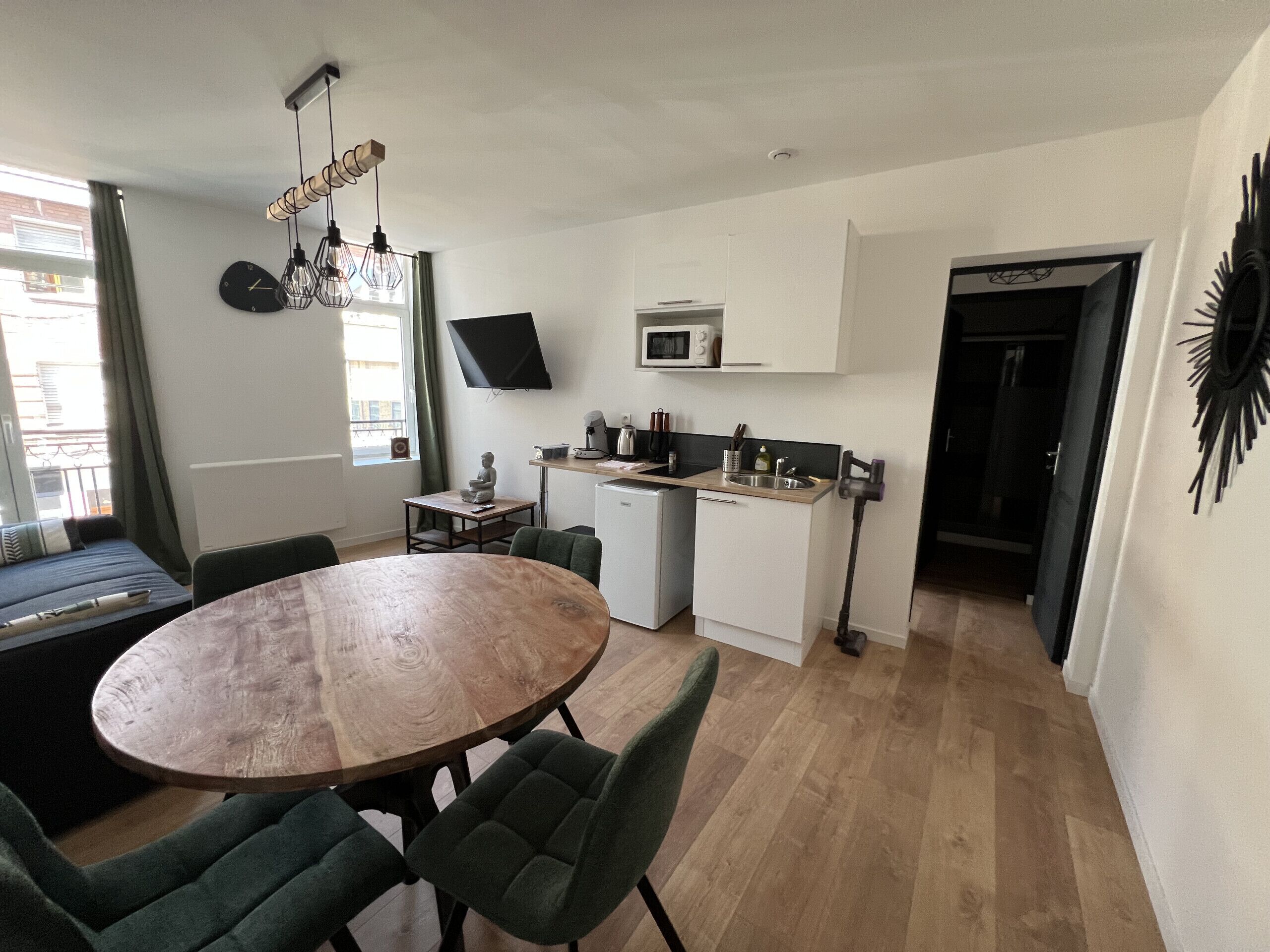 Un espace de vie compact comprenant un coin repas, une kitchenette et un téléviseur fixé au mur.
