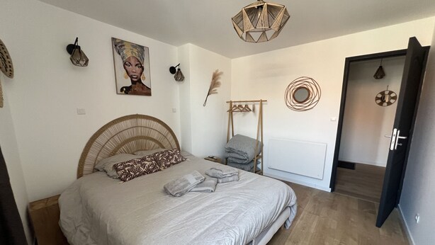 Un dormitorio con cama, armario, lámpara colgante y puerta.