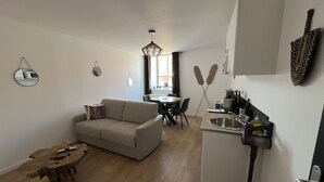 Un espacio habitable compacto con sofá, mesa de comedor y kitchenette.
